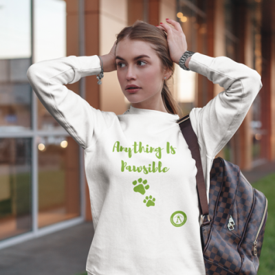 Lady wearing white sweatshirt with Anything is Pawsible written in green with green pawprints below it