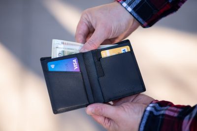 man taking bank notes from wallet with credit cards on show