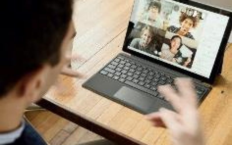Man at desk, laptop open, video conferencing with 4 others